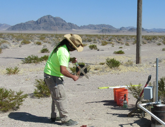 Hydrologist measuring depth to water with a hand-held steel tape in well Amargosa Desert 4b